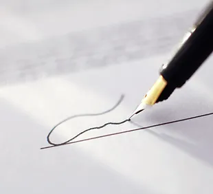 Pluma firmando una hoja